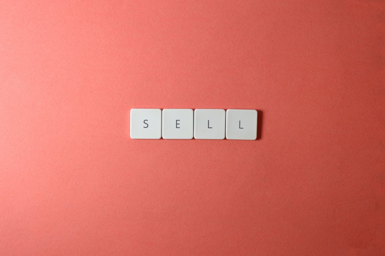 Close-up of keyboard tiles spelling 'sell' on a red background, minimalist design.